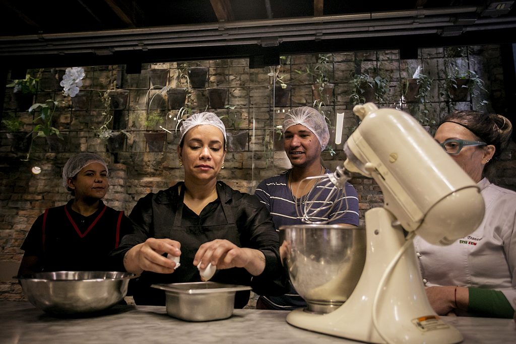 Grupo de pessoas em aula de culinário em cozinha industrial.