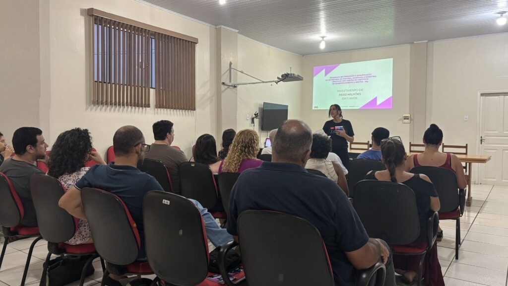 Foto de grupo de pessoas assistindo palestra em uma sala.