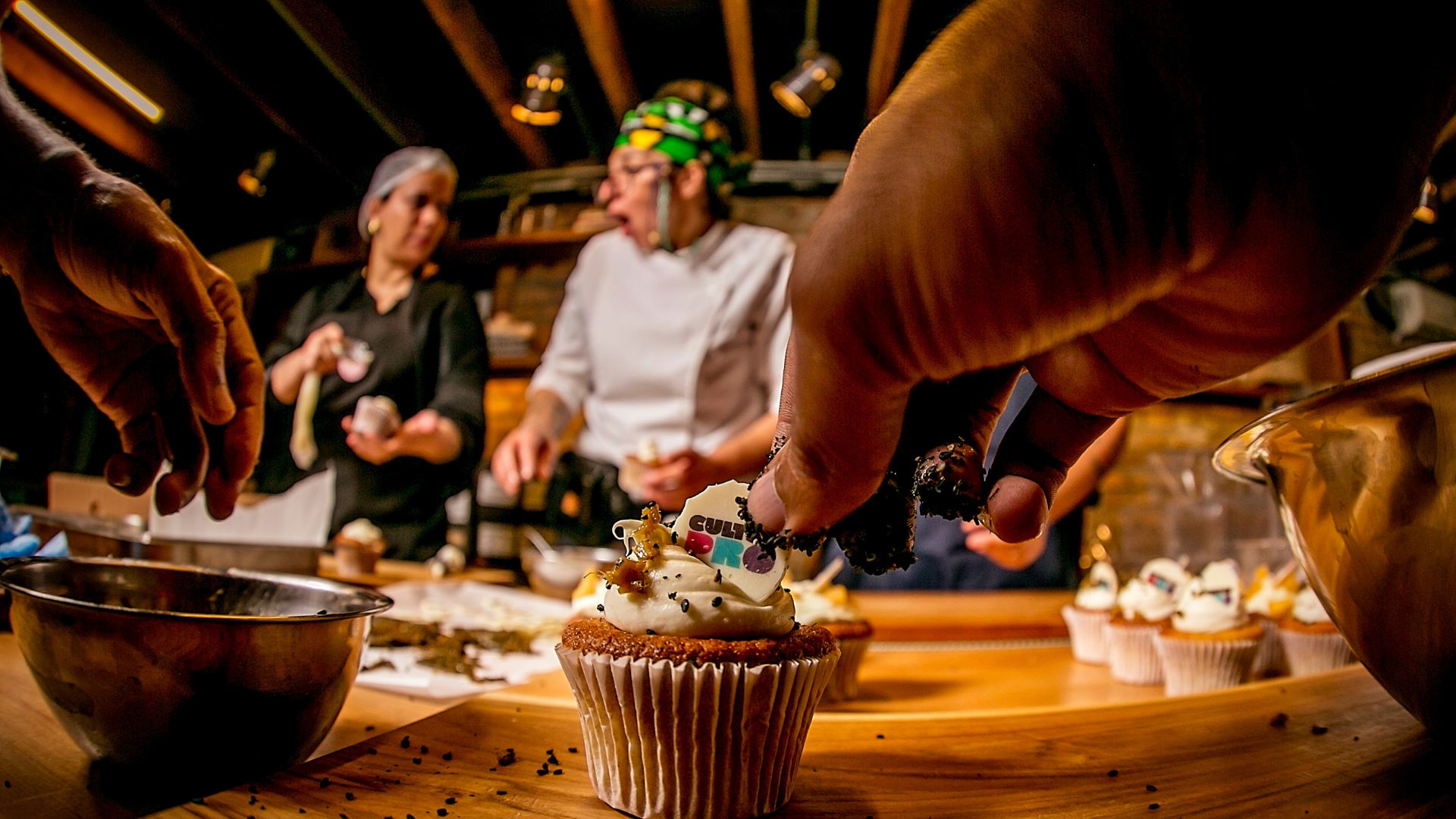 Foto de pessoa enfeitando com grãos o cupcake em cozinha industrial em restaurante.