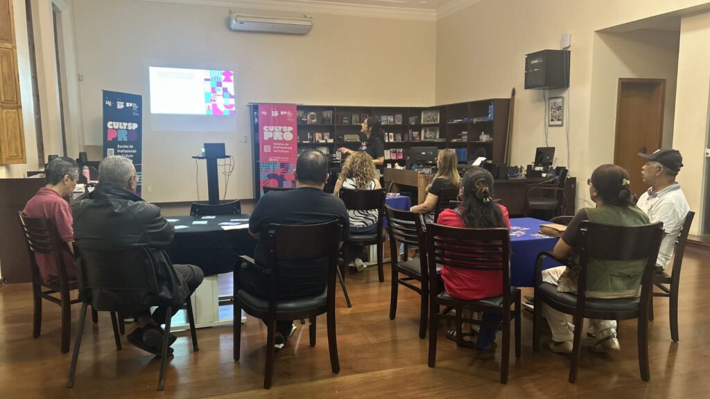 Foto de grupo de pessoas assistindo palestra de GIRO PRO em sala em prédio histórico.