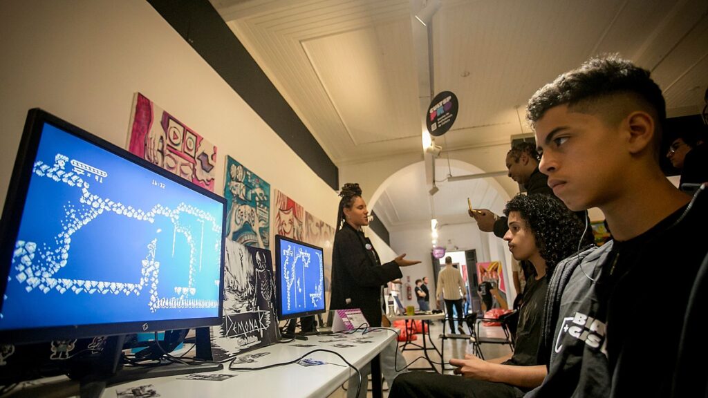 Foto de jovem na frente da tela de computador em evento na galeria do Oswald de Andrade.