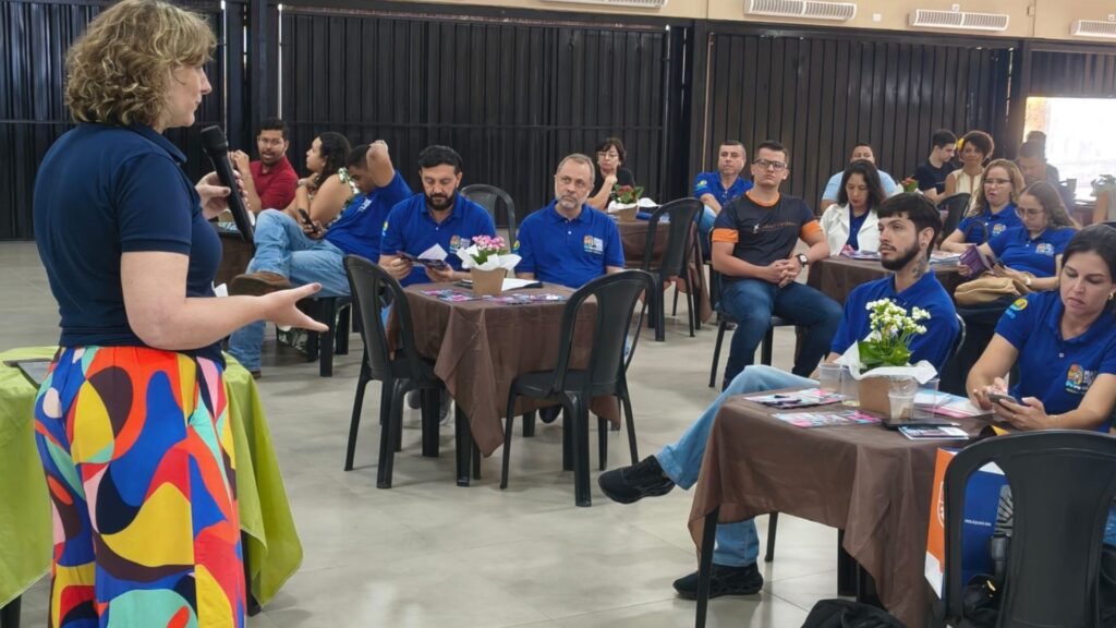 Foto de grupo de pessoas assistindo palestra de Paula Venâncio da atividade GIRO PRO em um salão.