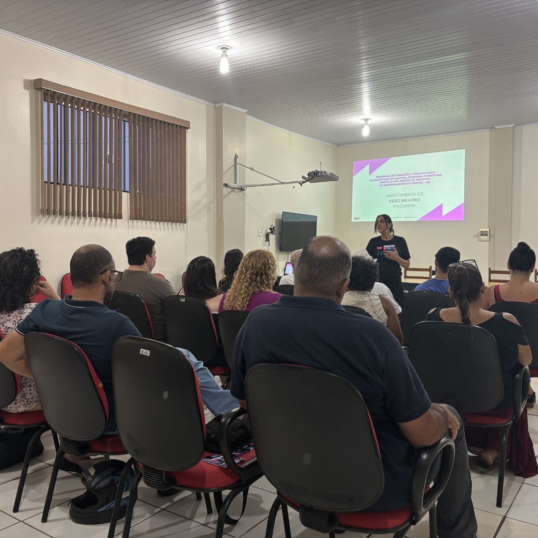 Foto de grupo de pessoas assistindo palestra em uma sala.