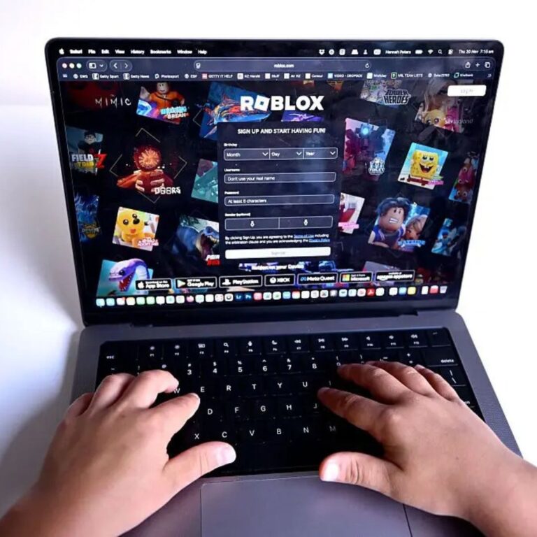 Foto das mãos de uma pessoa teclando um notebook com programa de games.